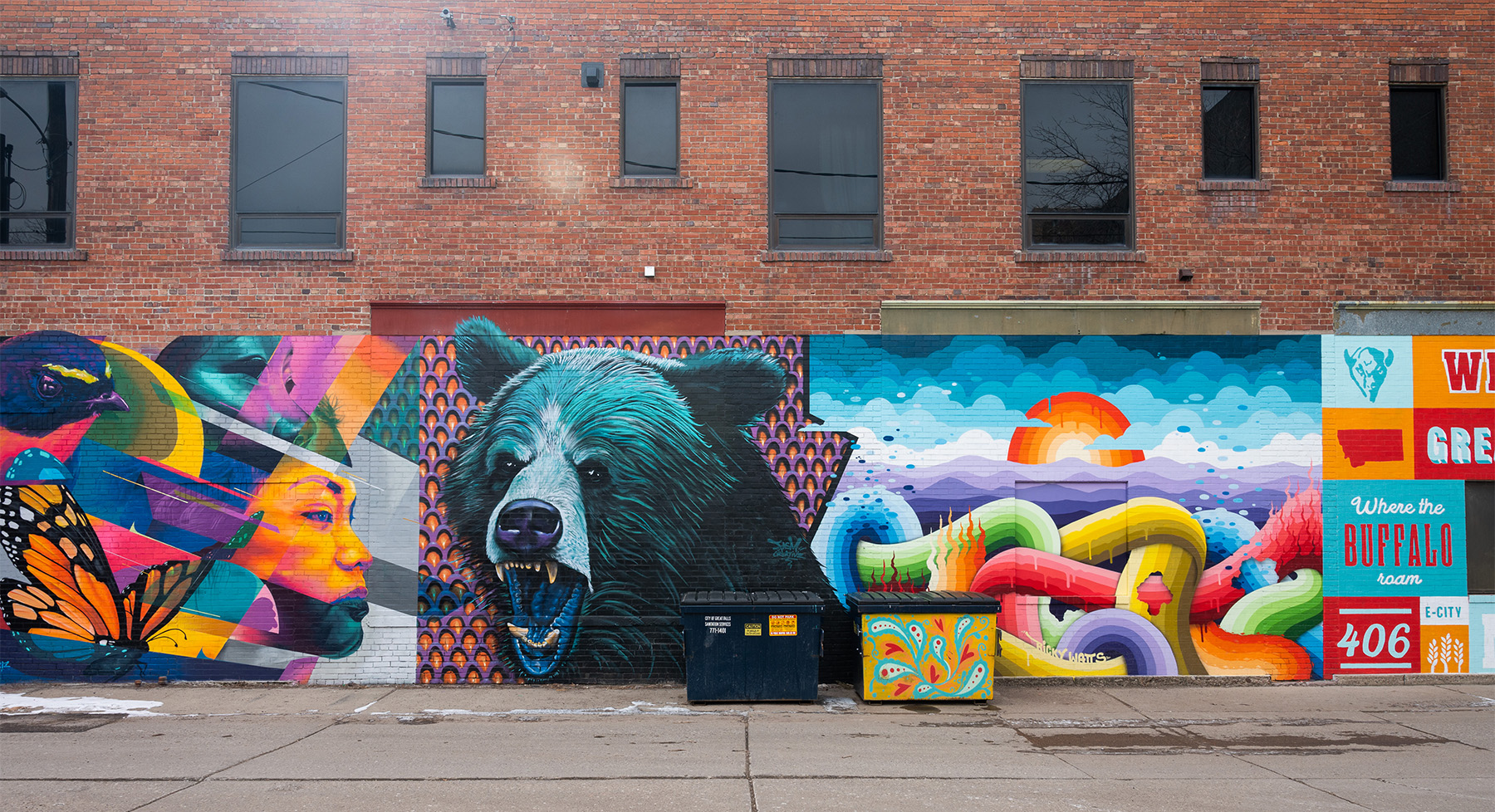 Series of murals on alley wall depicting abstract, colorful shapes, a grizzly bear, and intertwining tubular shapes